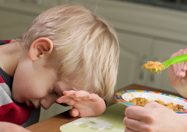 Boy being offered cereal on spoon and refusing